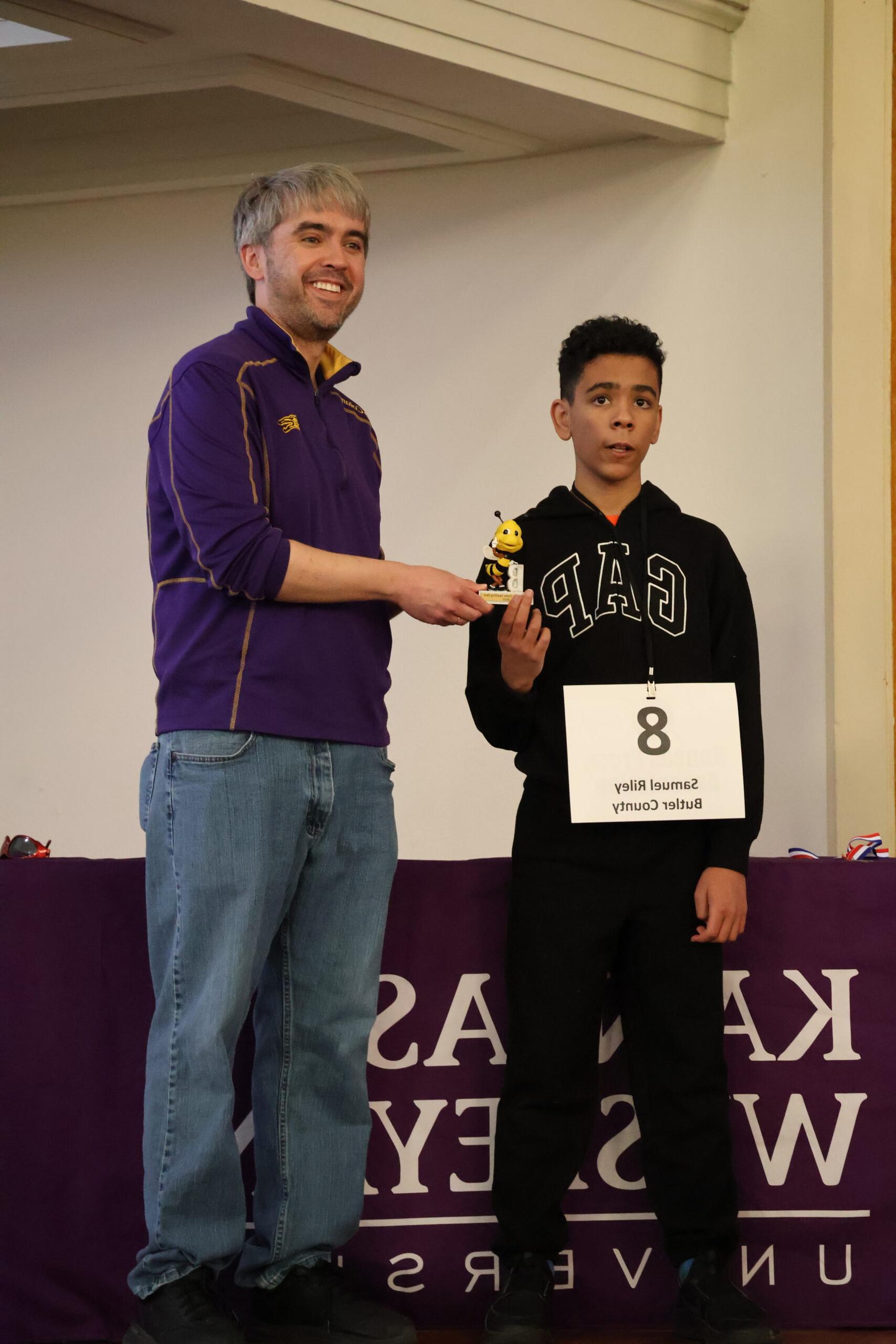 One male handing another a trophy